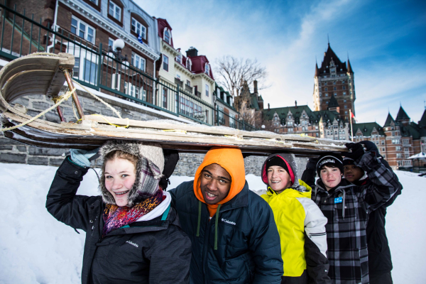 Students carrying a sled in Quebec winter setting.