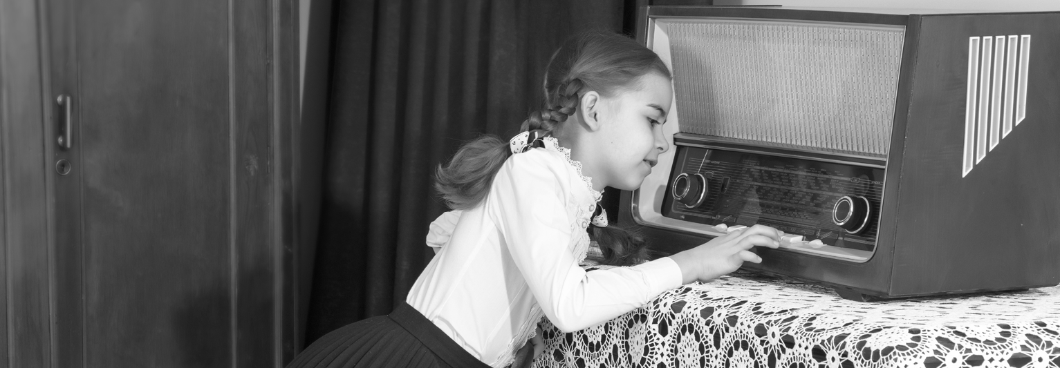 Black and white picture of a child playing with an AM radio